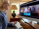 Woman wearing earbuds at her home  office desk uses SonicCloud software to enhance the sound of a videoconference on her computer